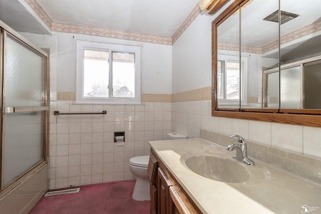 bathroom with vanity, toilet, and tile walls