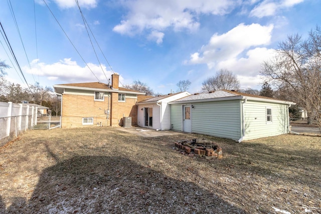 rear view of house with cooling unit and a fire pit