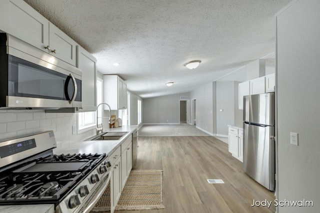 kitchen with white cabinetry, sink, backsplash, and stainless steel appliances