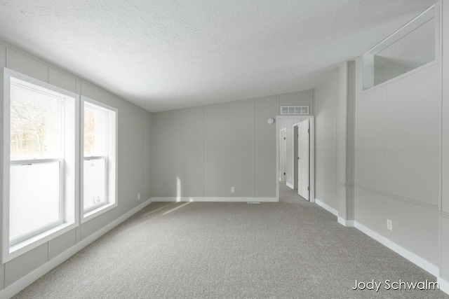 unfurnished room featuring a textured ceiling and carpet