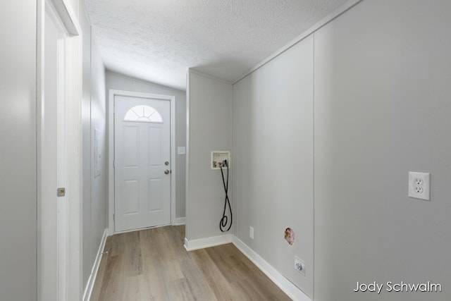 interior space with hookup for a washing machine, light hardwood / wood-style flooring, and a textured ceiling