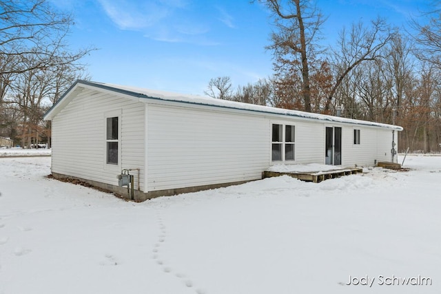 snow covered back of property featuring a deck