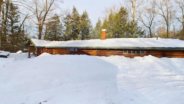 view of snowy exterior with a chimney