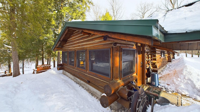 view of snowy exterior featuring log siding