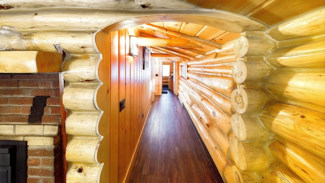 hallway with log walls, dark wood-type flooring, wooden ceiling, and beamed ceiling