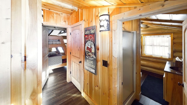 corridor with lofted ceiling with beams, dark wood-style floors, wooden walls, log walls, and wood ceiling