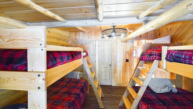 bedroom featuring beam ceiling, a chandelier, wood walls, and wood finished floors