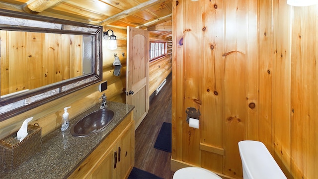 bathroom featuring toilet, vanity, wooden ceiling, wood finished floors, and log walls