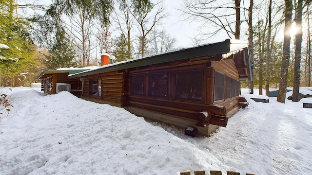 view of snowy exterior featuring ac unit and a chimney