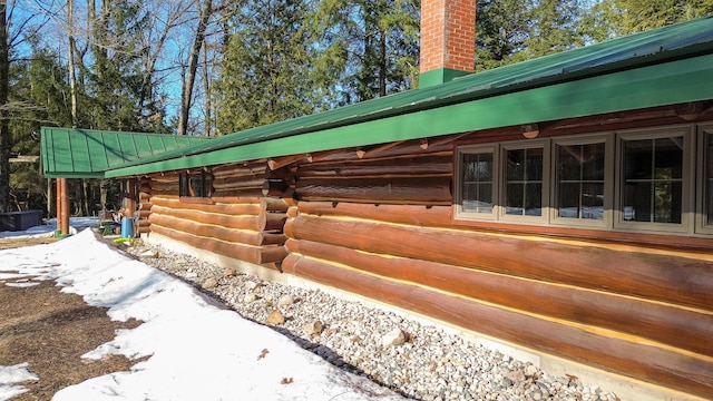 view of home's exterior with log siding, a chimney, and metal roof