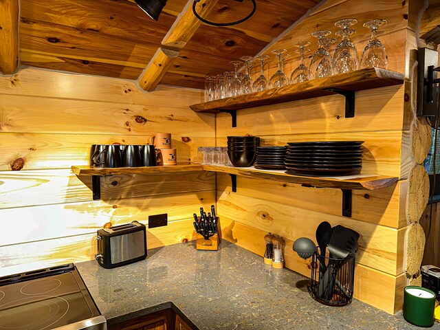 kitchen with beam ceiling, range, wood ceiling, and wood walls