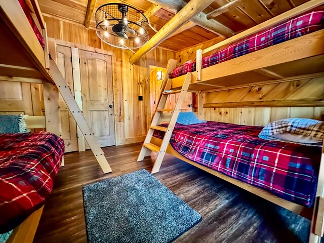 bedroom featuring wood ceiling, wooden walls, wood finished floors, and beamed ceiling