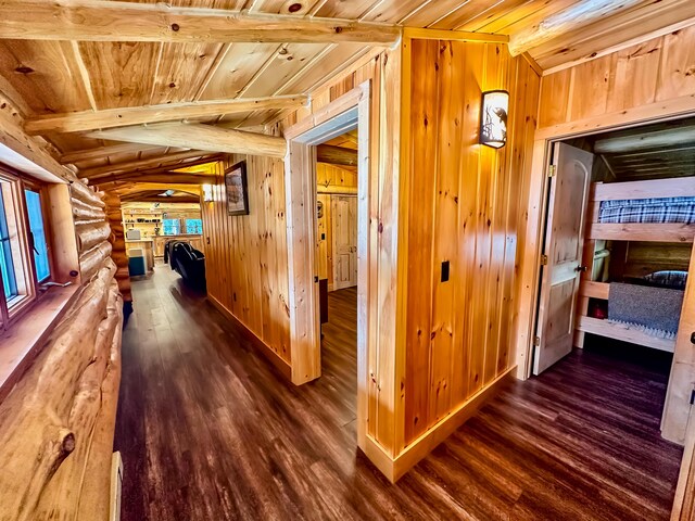 corridor with beam ceiling, dark wood-style floors, rustic walls, wood walls, and wood ceiling