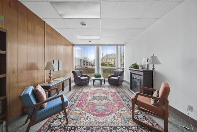 sitting room with a wall of windows, wooden walls, and a paneled ceiling