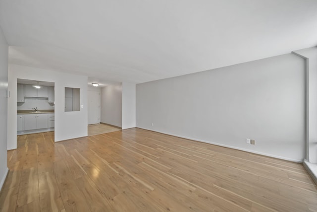 unfurnished living room featuring sink and light hardwood / wood-style floors