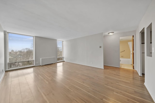 spare room featuring radiator, light hardwood / wood-style flooring, and expansive windows