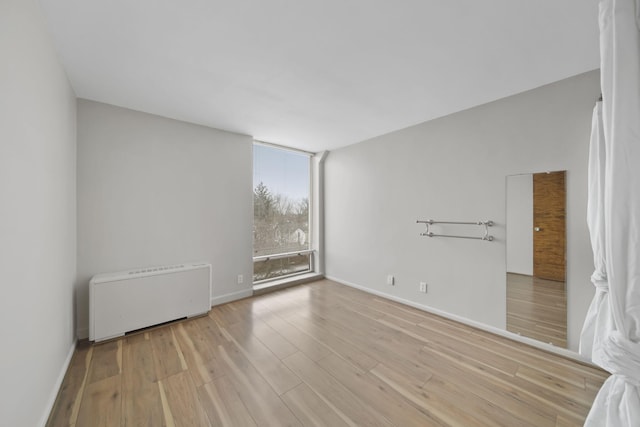 empty room featuring radiator heating unit, light hardwood / wood-style floors, and floor to ceiling windows