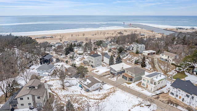 snowy aerial view with a water view and a view of the beach