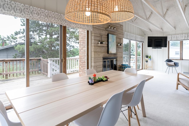 carpeted dining space featuring a fireplace and vaulted ceiling with beams