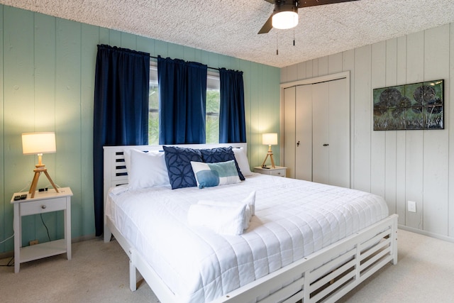 bedroom with ceiling fan, light colored carpet, a closet, and a textured ceiling