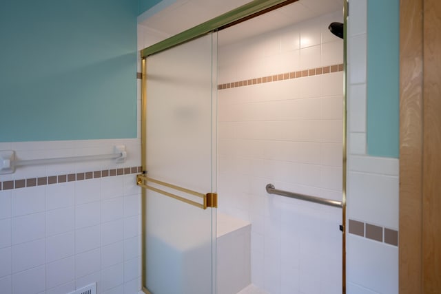 bathroom with an enclosed shower and tile walls