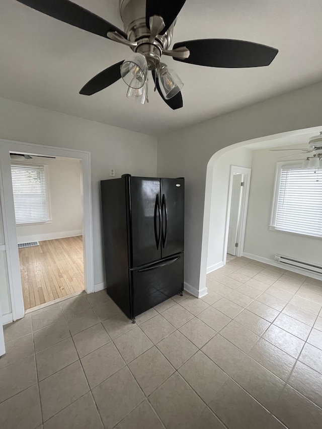 kitchen featuring black refrigerator, light tile patterned floors, ceiling fan, and a baseboard heating unit