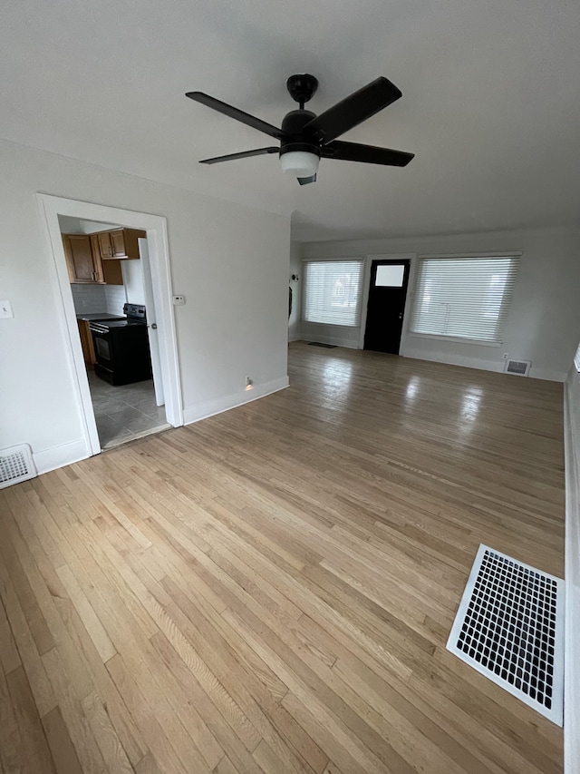 unfurnished living room featuring ceiling fan and light wood-type flooring