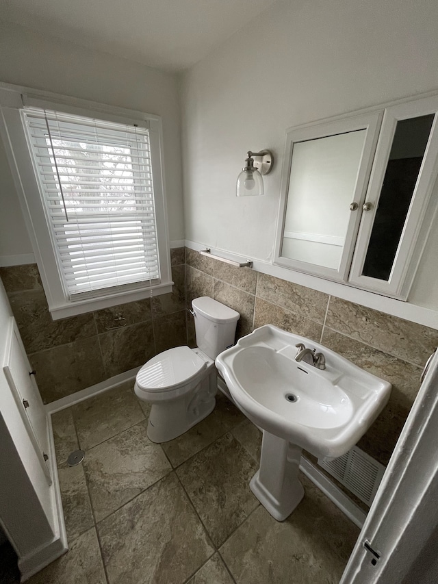 bathroom with toilet and tile walls