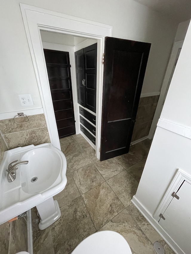 bathroom with tile walls and toilet