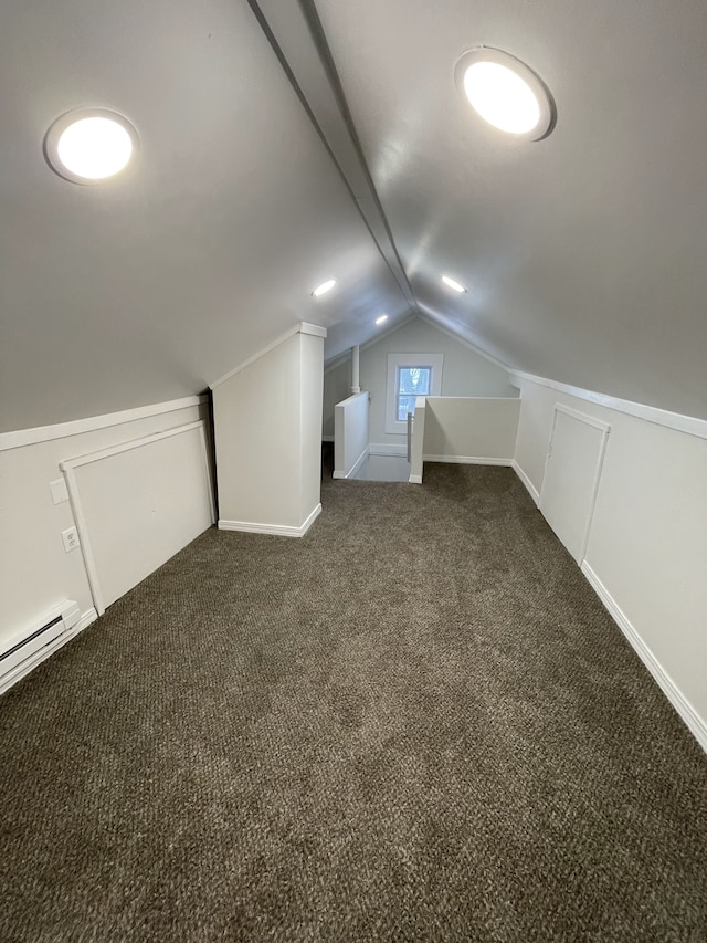 additional living space with dark carpet and vaulted ceiling