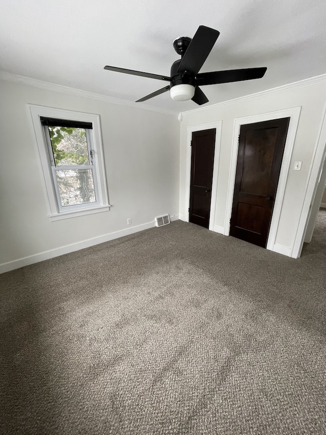 unfurnished bedroom with dark colored carpet, crown molding, two closets, and ceiling fan