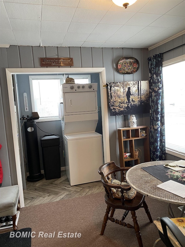 laundry area featuring light parquet floors and stacked washing maching and dryer