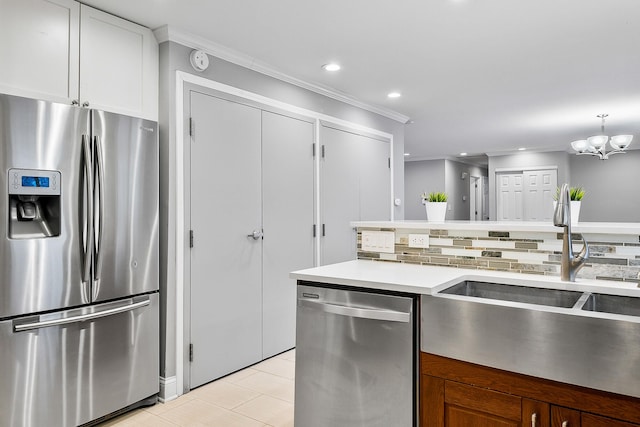 kitchen with decorative light fixtures, sink, white cabinets, ornamental molding, and stainless steel appliances