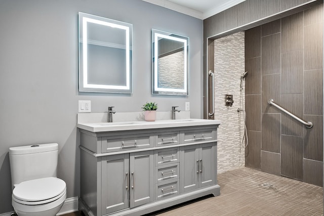 bathroom featuring vanity, ornamental molding, toilet, and a tile shower