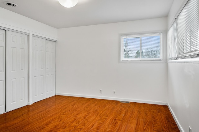 unfurnished bedroom with hardwood / wood-style flooring and two closets