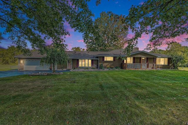 ranch-style house featuring covered porch, driveway, a front lawn, and an attached garage