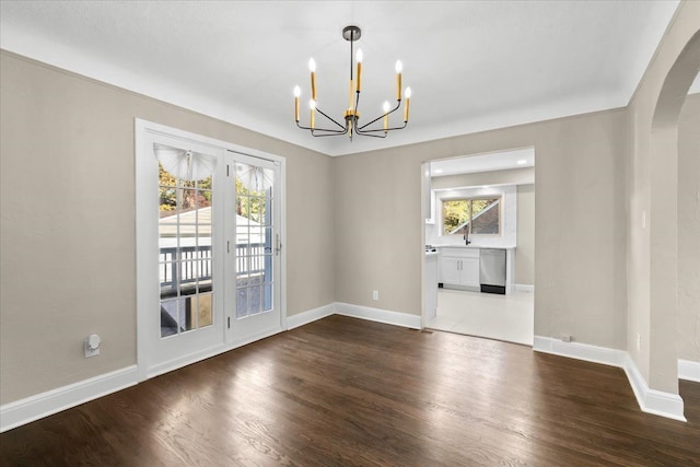 unfurnished dining area with dark wood-type flooring and an inviting chandelier