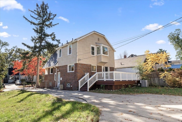 view of front property with central AC unit, a front lawn, and a deck