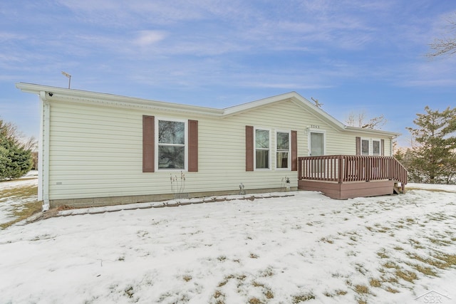 snow covered back of property with a wooden deck