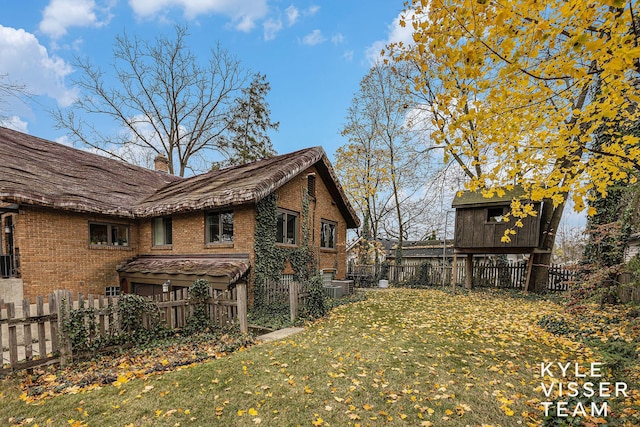 view of home's exterior with fence private yard, brick siding, and a lawn