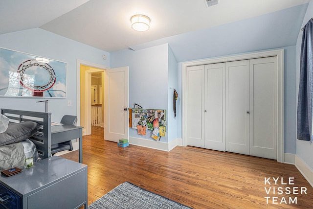 office space featuring light wood-style floors, visible vents, vaulted ceiling, and baseboards