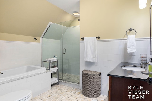 bathroom featuring tile walls, a stall shower, vaulted ceiling, vanity, and a bath