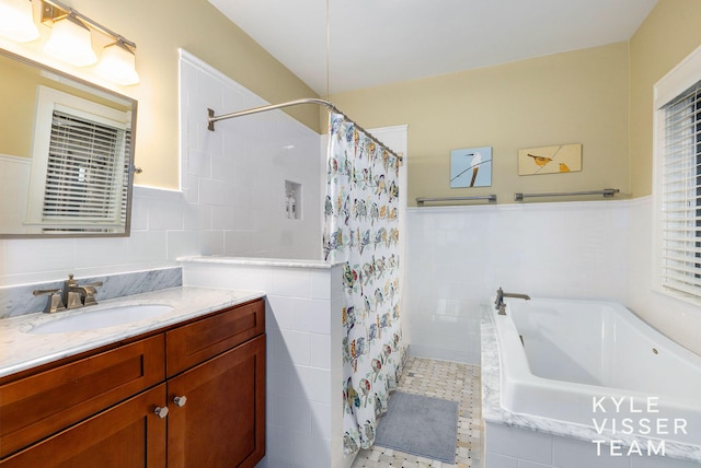 full bathroom with a wainscoted wall, vanity, tile walls, tiled shower, and tiled tub