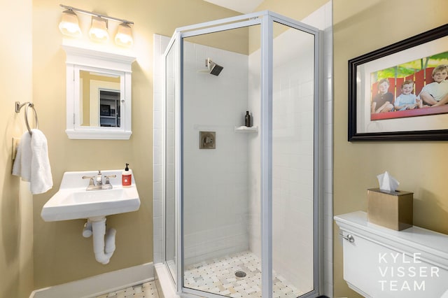 bathroom with a stall shower, a sink, and toilet