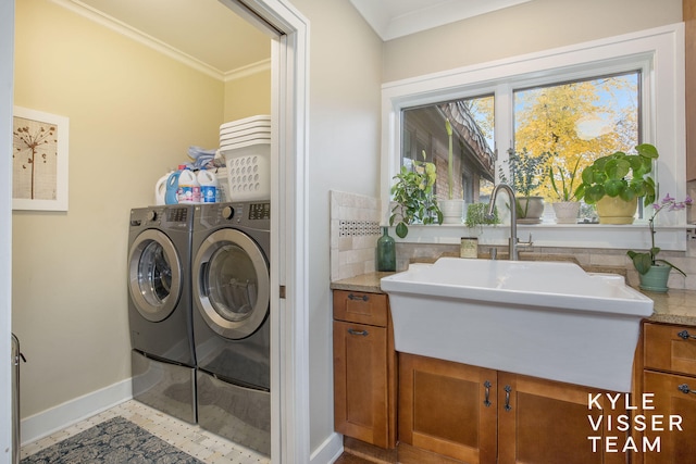 clothes washing area featuring ornamental molding, a sink, laundry area, independent washer and dryer, and baseboards