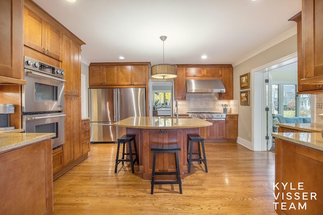 kitchen with appliances with stainless steel finishes, range hood, and brown cabinets