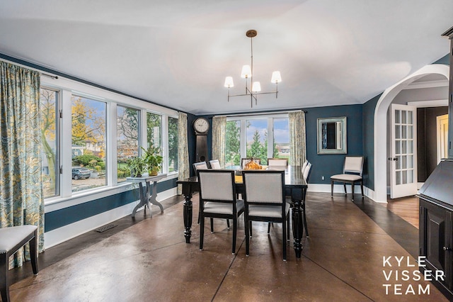 dining space with baseboards, arched walkways, visible vents, finished concrete floors, and a chandelier