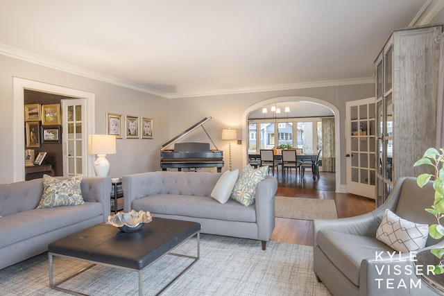 living area featuring arched walkways, ornamental molding, wood finished floors, and french doors