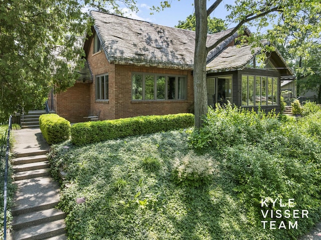 2346 Lake Dr SE, East Grand Rapids, MI 49506 - view of home's exterior with a sunroom, brick siding, and stairs