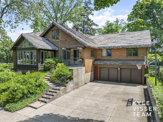 2346 Lake Dr SE, East Grand Rapids, MI 49506 - view of front of house with concrete driveway, an attached garage, brick siding, and a chimney